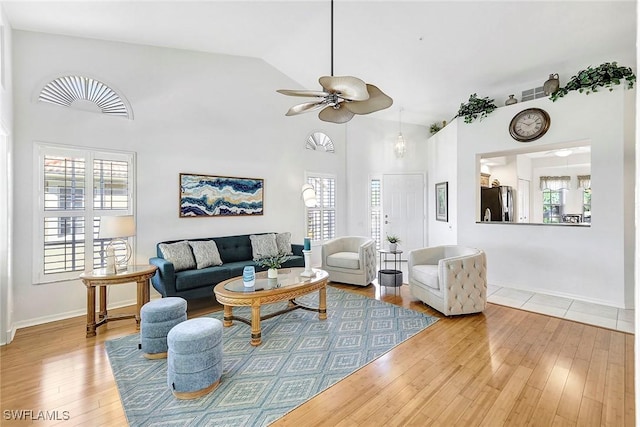 living room featuring wood-type flooring, high vaulted ceiling, ceiling fan, and a healthy amount of sunlight