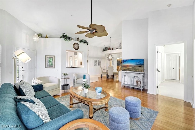 living room featuring ceiling fan with notable chandelier, wood-type flooring, and high vaulted ceiling