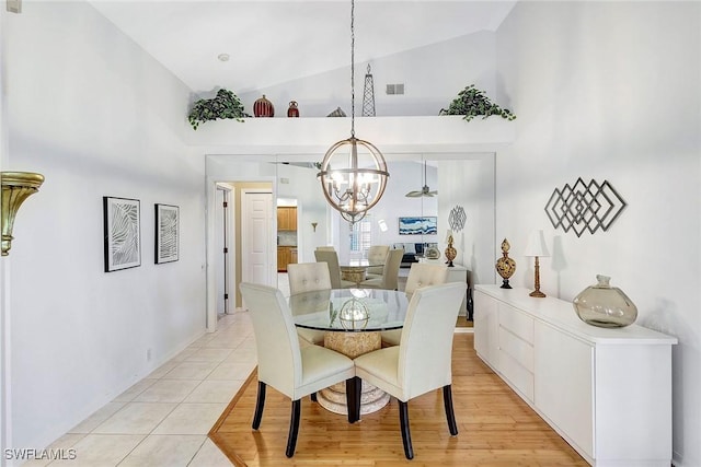 tiled dining area featuring a chandelier and high vaulted ceiling