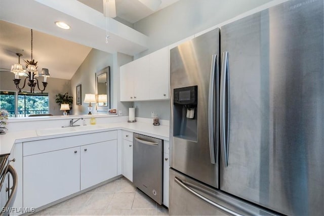 kitchen with vaulted ceiling, light tile patterned floors, white cabinetry, stainless steel appliances, and a chandelier