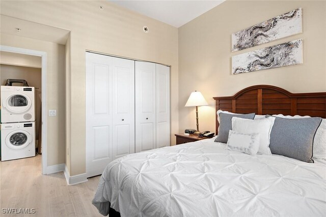 bedroom featuring light hardwood / wood-style floors, stacked washer and dryer, and a closet