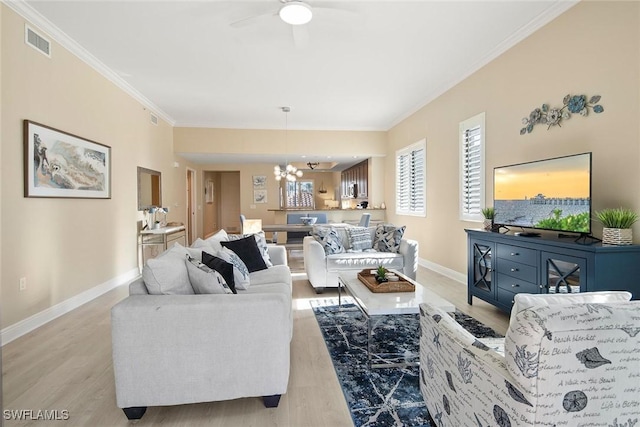 living room with ceiling fan with notable chandelier, light wood-type flooring, and ornamental molding