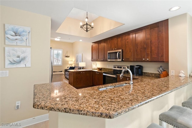 kitchen with kitchen peninsula, stainless steel appliances, sink, pendant lighting, and an inviting chandelier