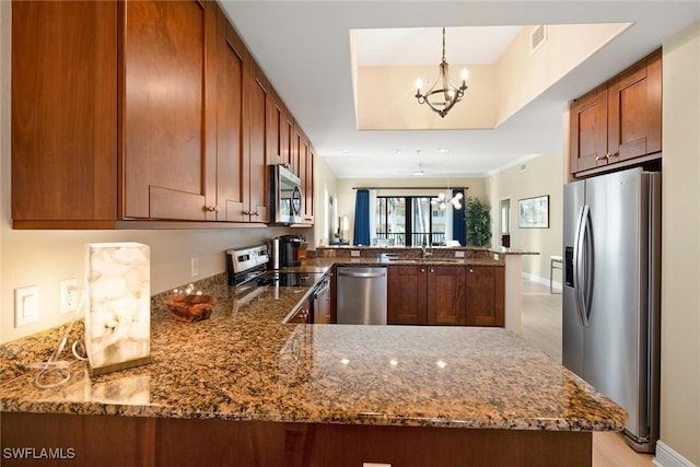 kitchen featuring stainless steel appliances, kitchen peninsula, dark stone countertops, pendant lighting, and ceiling fan with notable chandelier