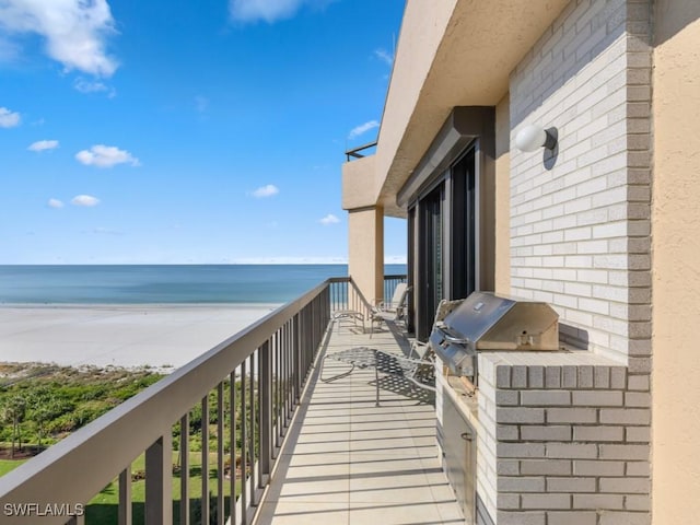 balcony with area for grilling, a water view, and a view of the beach