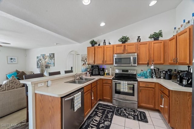 kitchen featuring kitchen peninsula, sink, appliances with stainless steel finishes, and vaulted ceiling