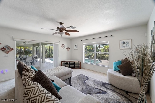 living room featuring light carpet, a textured ceiling, and ceiling fan