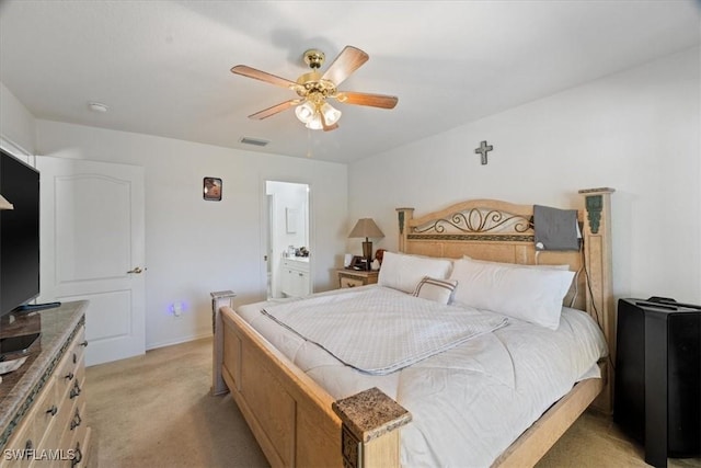 bedroom featuring ceiling fan, ensuite bathroom, and light colored carpet