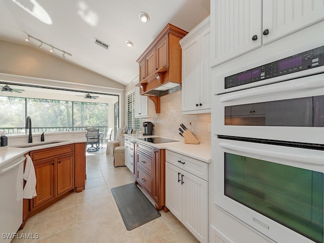 kitchen with appliances with stainless steel finishes, tasteful backsplash, sink, light tile patterned floors, and lofted ceiling