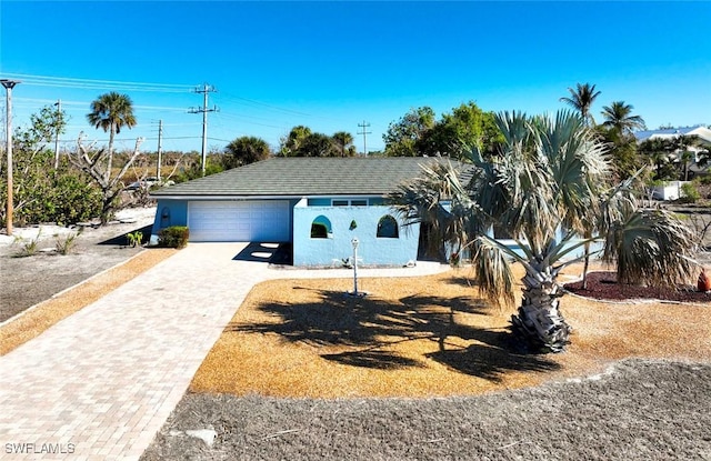 view of front of property featuring decorative driveway, an attached garage, and stucco siding