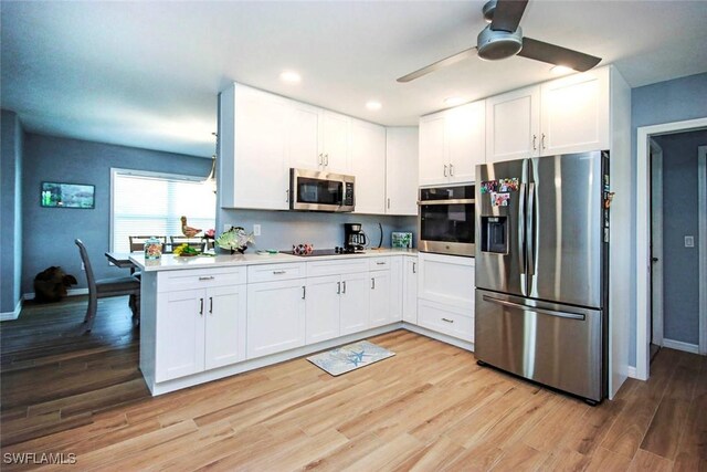 kitchen with light wood-type flooring, stainless steel appliances, white cabinetry, and ceiling fan