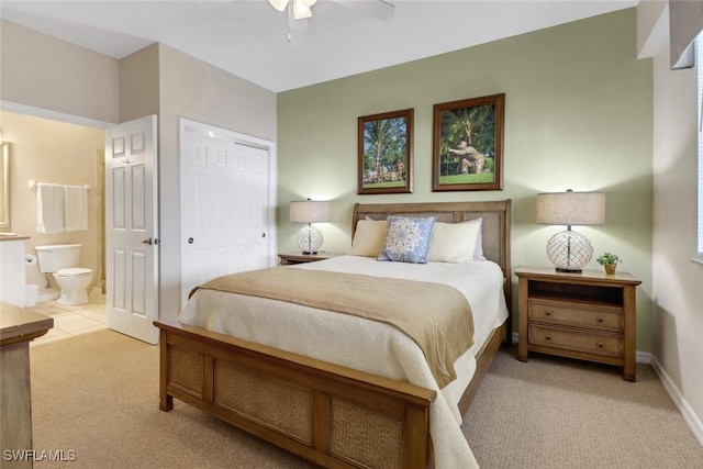 bedroom featuring ensuite bathroom, a closet, light colored carpet, and ceiling fan