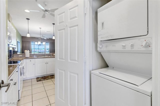 laundry area with ceiling fan, stacked washing maching and dryer, sink, and light tile patterned floors