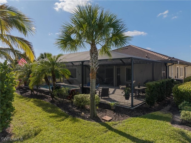 rear view of property with a lanai, a yard, and a patio