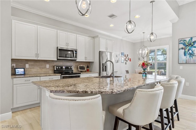 kitchen with a kitchen island with sink, white cabinets, and stainless steel appliances