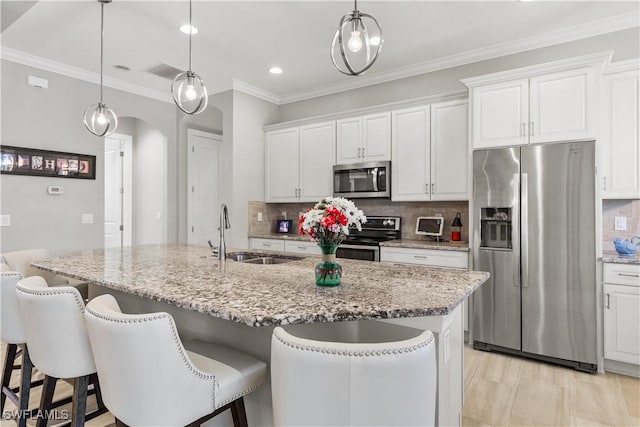 kitchen with tasteful backsplash, stainless steel appliances, sink, white cabinets, and an island with sink