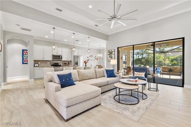 living room featuring ceiling fan, crown molding, and sink