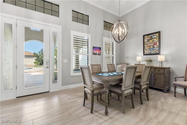 dining room featuring light hardwood / wood-style floors, ornamental molding, a towering ceiling, and an inviting chandelier