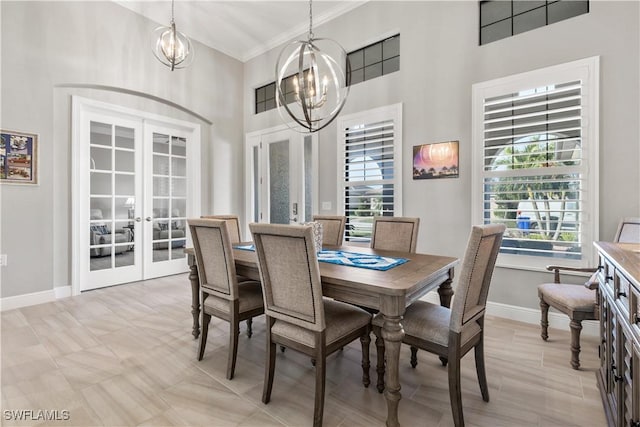 dining space featuring french doors, a towering ceiling, ornamental molding, and an inviting chandelier