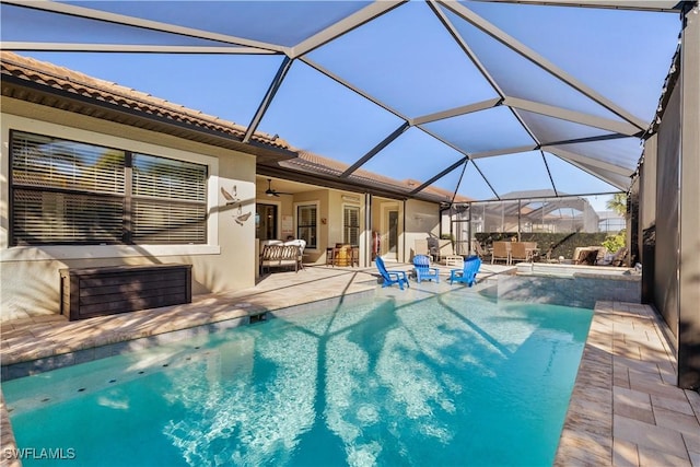 view of swimming pool featuring ceiling fan, a patio area, and a lanai