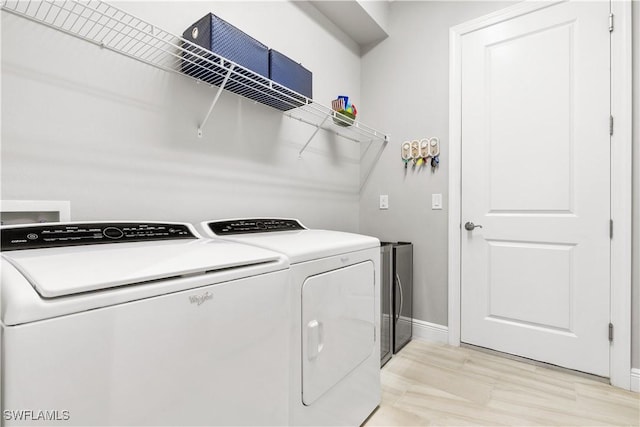 laundry room with washer and clothes dryer and light hardwood / wood-style flooring