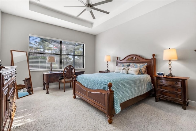 carpeted bedroom with a raised ceiling and ceiling fan