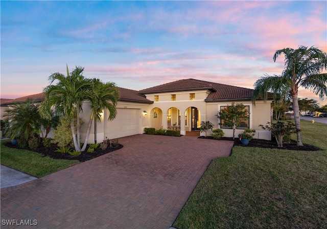 mediterranean / spanish home featuring covered porch, a garage, and a yard