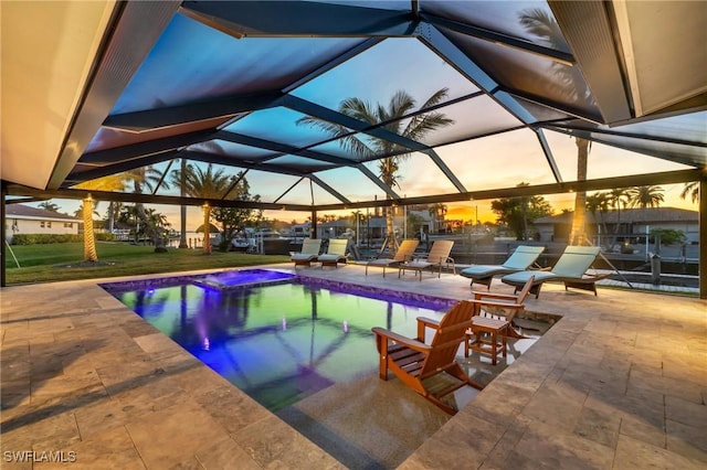 pool at dusk with a lanai and a patio