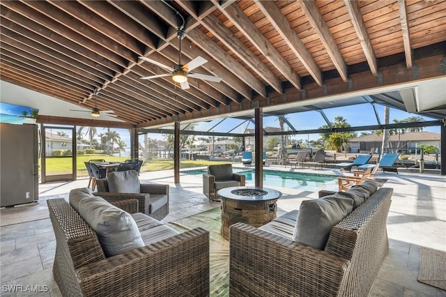 view of patio featuring glass enclosure, ceiling fan, and an outdoor living space with a fire pit