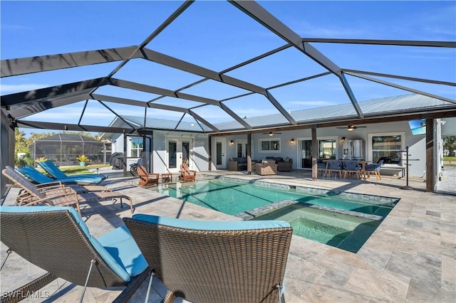 view of swimming pool with glass enclosure, ceiling fan, a patio area, and an in ground hot tub