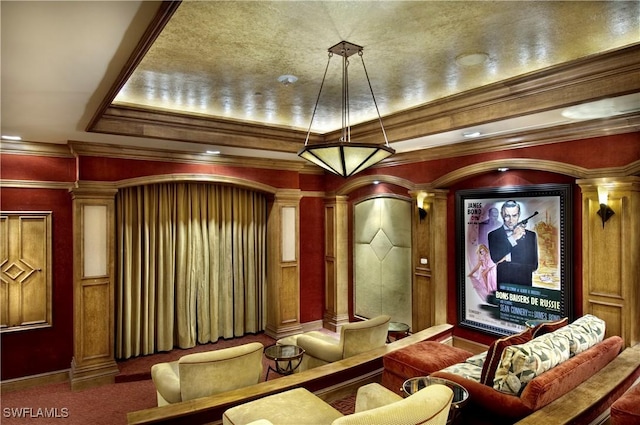 home theater featuring carpet, a raised ceiling, ornate columns, and ornamental molding