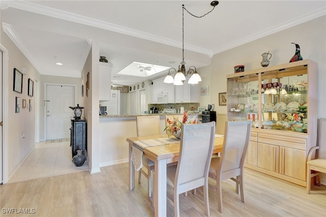 dining area with an inviting chandelier, a skylight, crown molding, and light hardwood / wood-style flooring