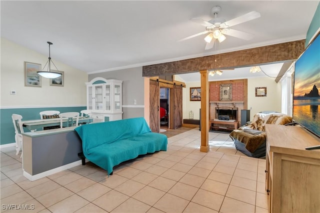 living room featuring lofted ceiling, crown molding, ceiling fan, a barn door, and light tile patterned floors