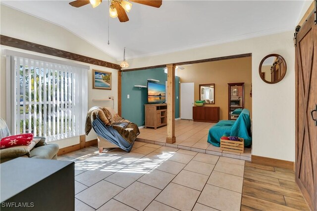 sitting room with a barn door, ceiling fan, light tile patterned flooring, and vaulted ceiling