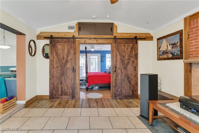 entrance foyer with a barn door, vaulted ceiling, ceiling fan, and crown molding