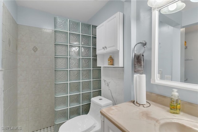 bathroom featuring toilet, vanity, tile walls, and walk in shower