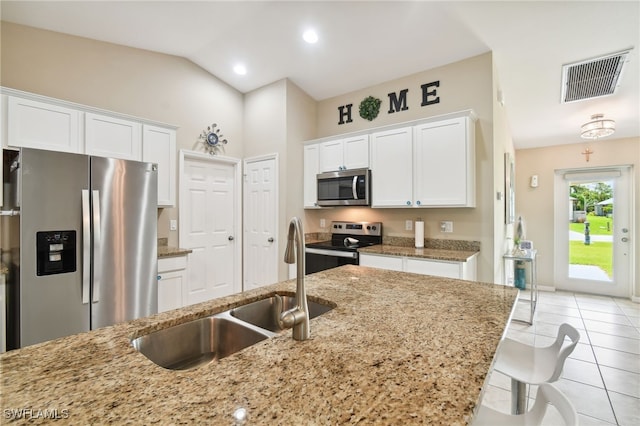 kitchen featuring white cabinets, sink, vaulted ceiling, light tile patterned floors, and appliances with stainless steel finishes