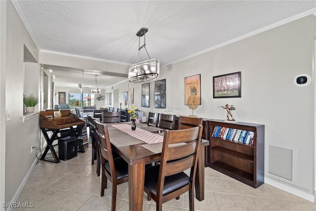 dining room with a notable chandelier, light tile patterned flooring, a textured ceiling, and ornamental molding