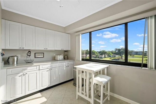 kitchen with white cabinets, ornamental molding, and light tile patterned flooring