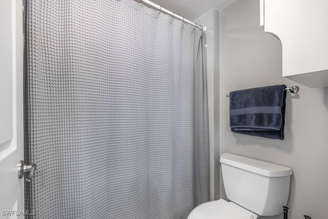 bathroom with a shower with curtain and toilet