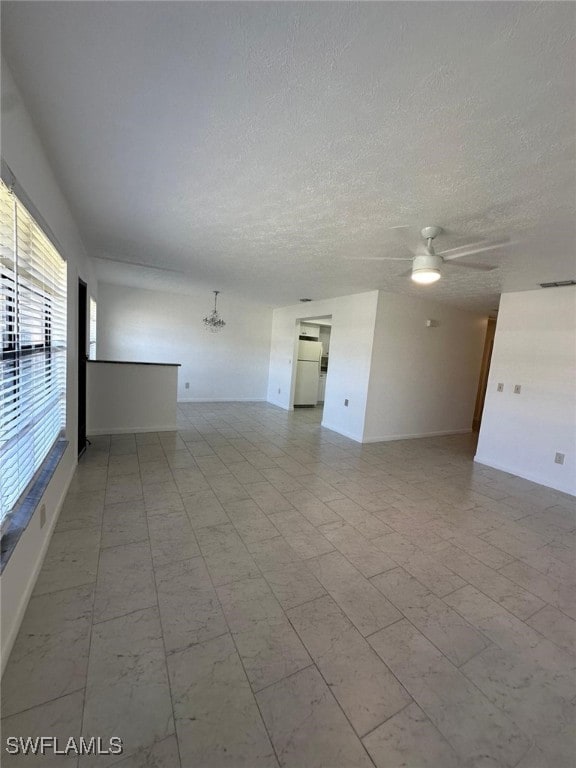 empty room with ceiling fan and a textured ceiling