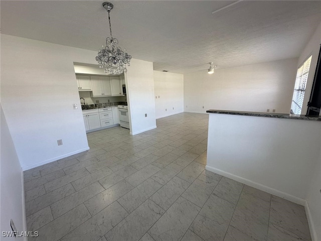 kitchen with sink, white electric stove, hanging light fixtures, white cabinetry, and a chandelier