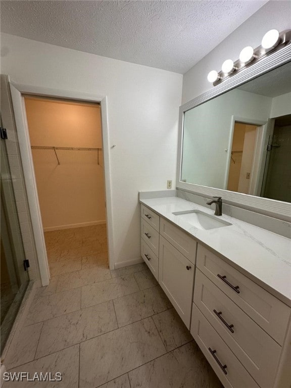 bathroom with vanity, an enclosed shower, and a textured ceiling