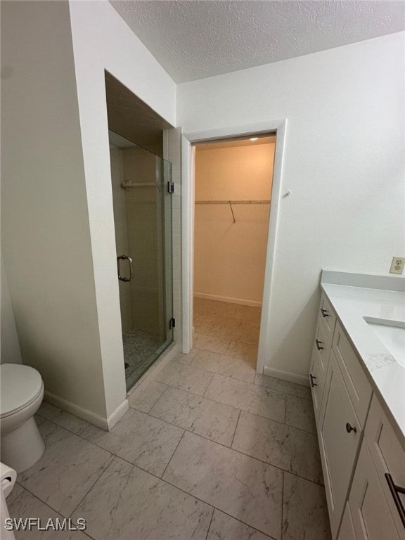 bathroom with toilet, vanity, a textured ceiling, and walk in shower