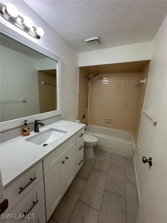 full bathroom with tiled shower / bath, vanity, a textured ceiling, and toilet