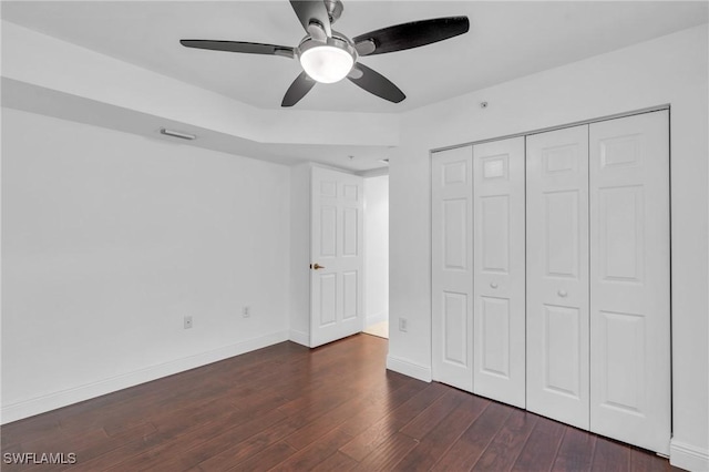 unfurnished bedroom with ceiling fan, dark wood-type flooring, and a closet