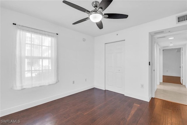 unfurnished bedroom with a closet, dark hardwood / wood-style floors, and ceiling fan