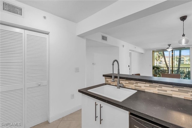 kitchen with pendant lighting, backsplash, sink, light tile patterned floors, and white cabinetry