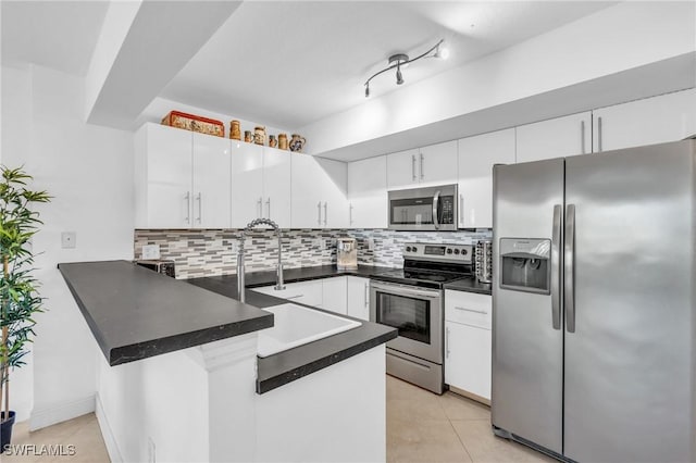 kitchen featuring backsplash, white cabinets, light tile patterned floors, appliances with stainless steel finishes, and kitchen peninsula