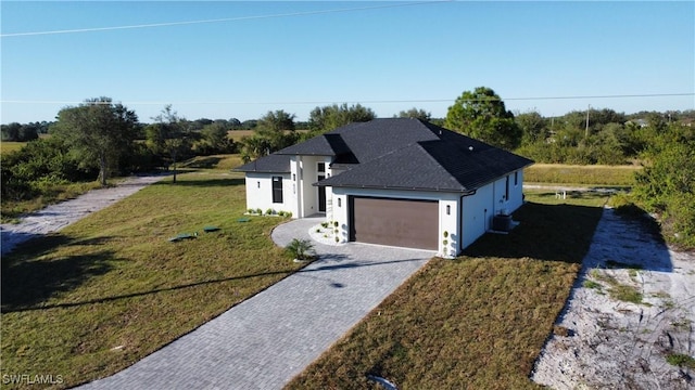 view of front of home featuring central AC unit, a garage, and a front yard